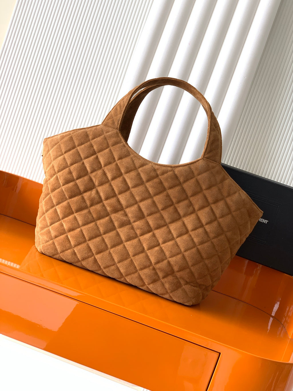 Quilted tan handbag with curved top handles and structured diamond pattern