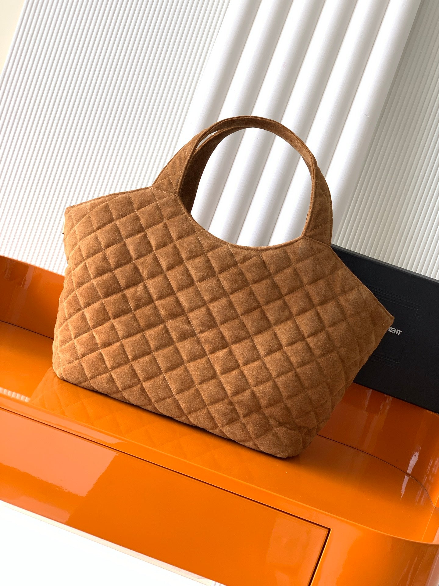 Quilted tan handbag with curved top handles and structured diamond pattern