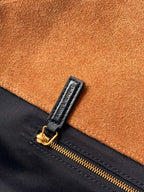 Tan suede and black zipper area with gold zipper pull on handbag