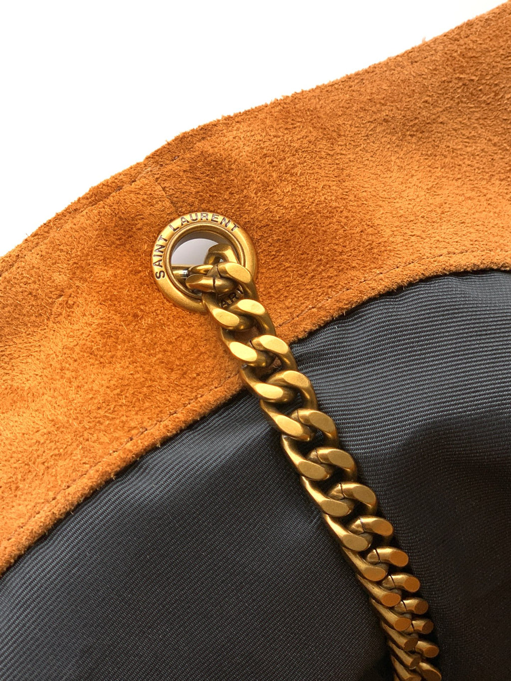 YSL bag zipper pull area with gold chain and round logo charm on tan suede
