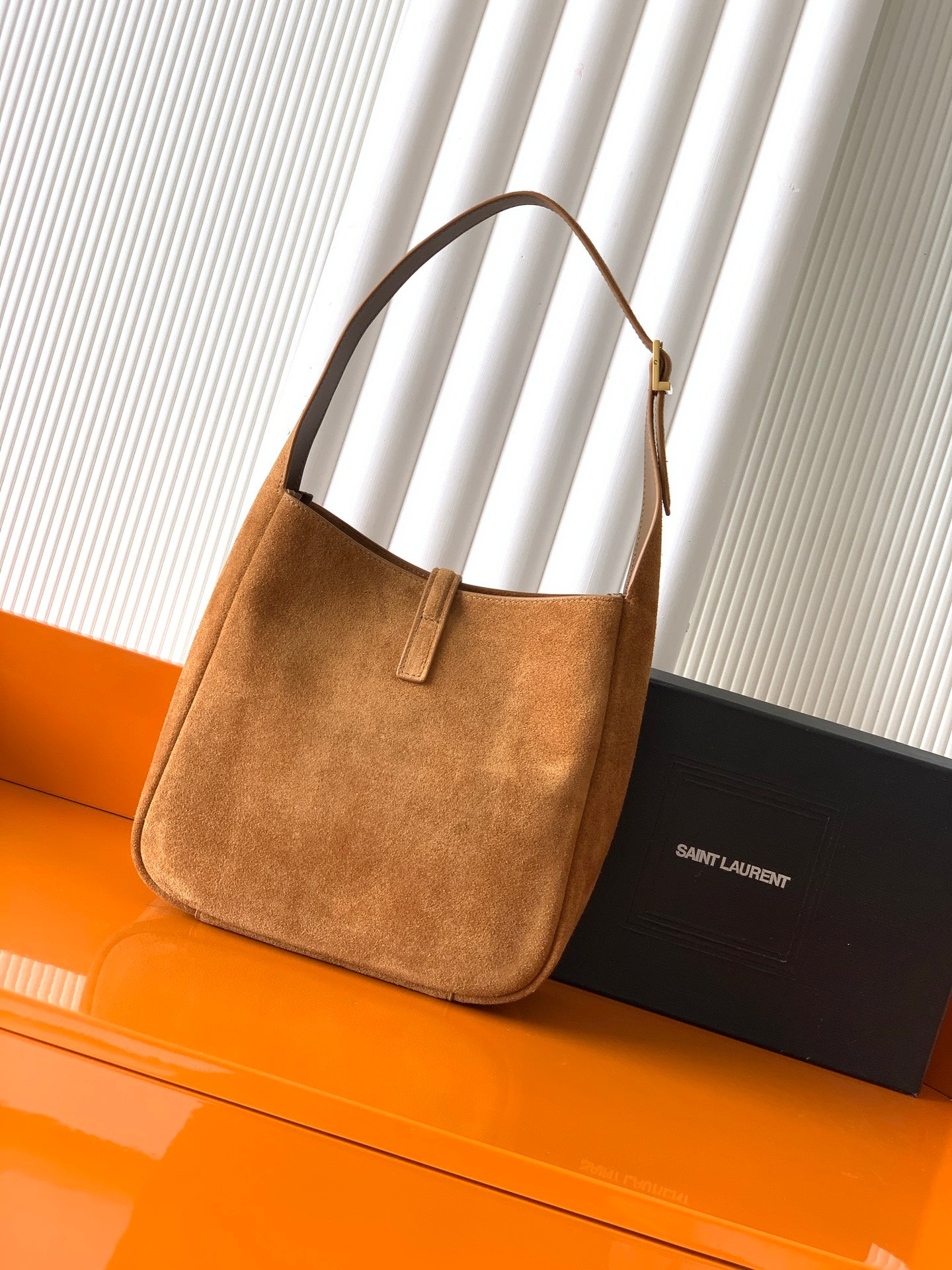 Tan suede hobo bag with loop handle and front vertical strap detail