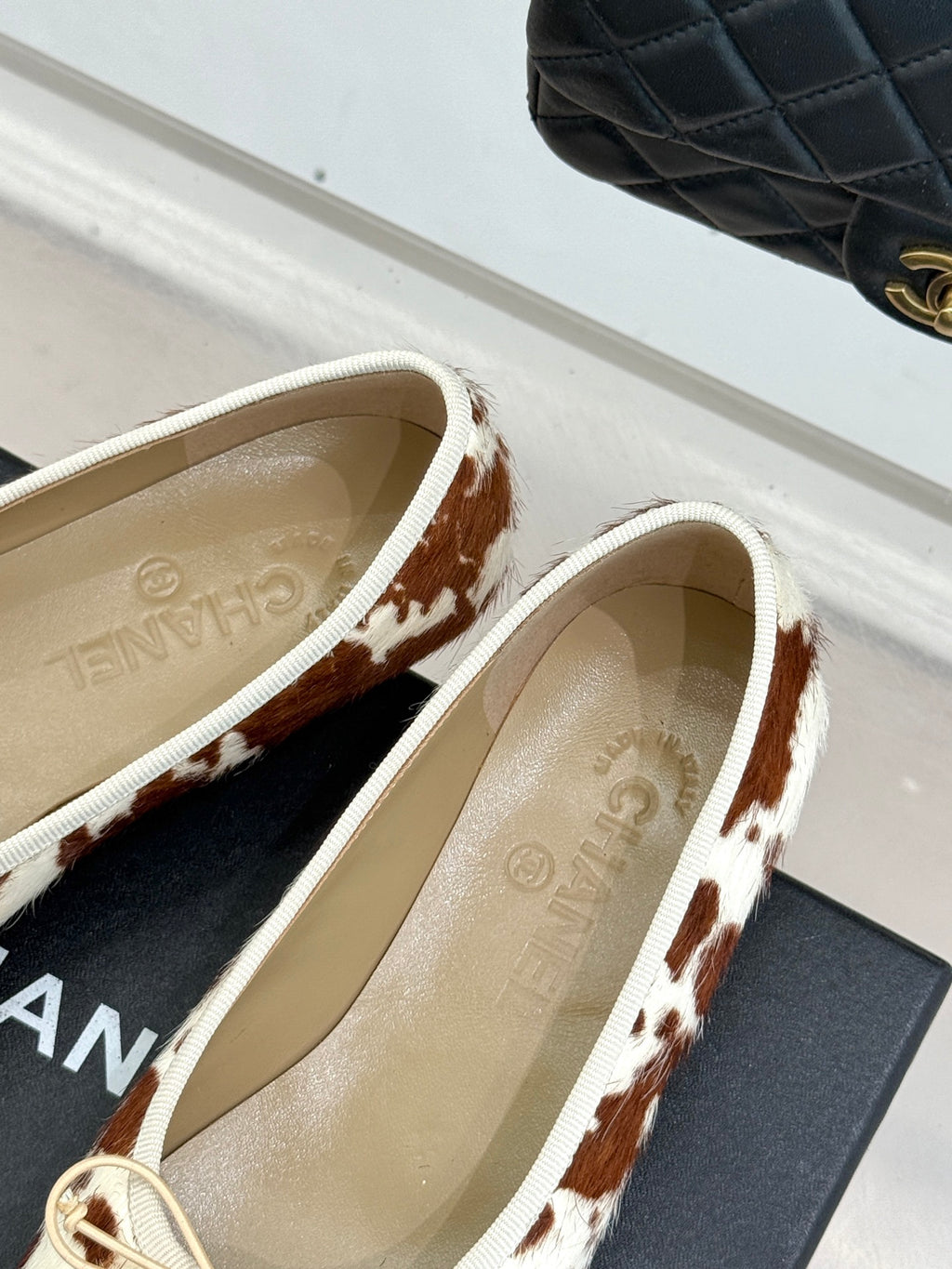Side view of cow-print ballet flats with cream laces and metal hardware