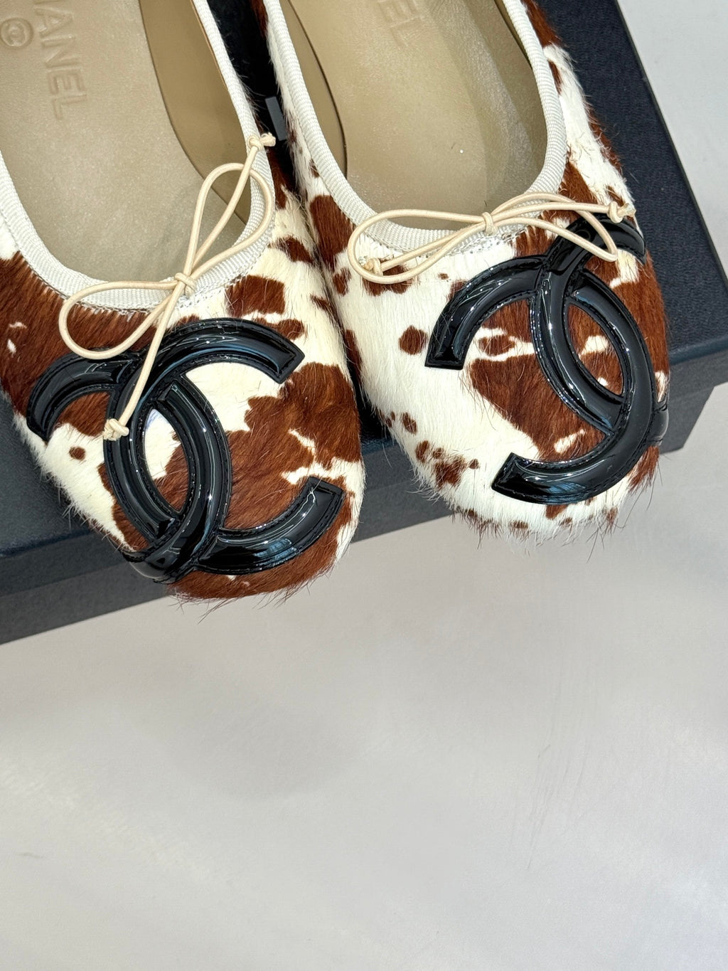 Close-up of cow-print ballet flats with cream laces and metal hardware
