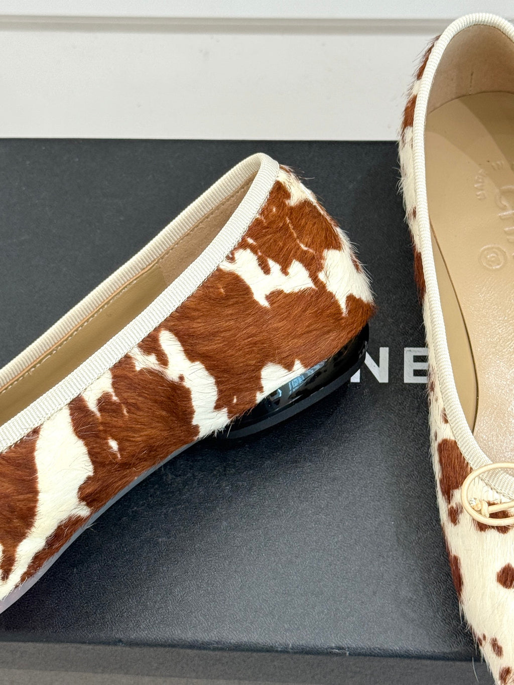 Close-up of cow-print ballet flat with cream lace and textured fabric