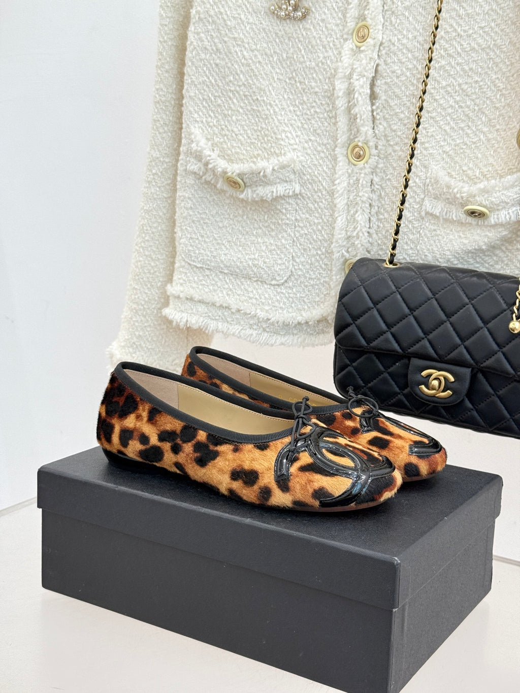 Leopard-print ballet flats with black logo appliqué and lace-up front detail.