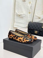 Leopard-print ballet flats with black logo appliqué and lace-up front detail.