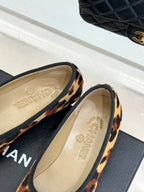 Leopard-print flats with beige insole showing logo text, side view.