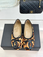 Pair of leopard-print flats with black logo appliqué and lace-up front.