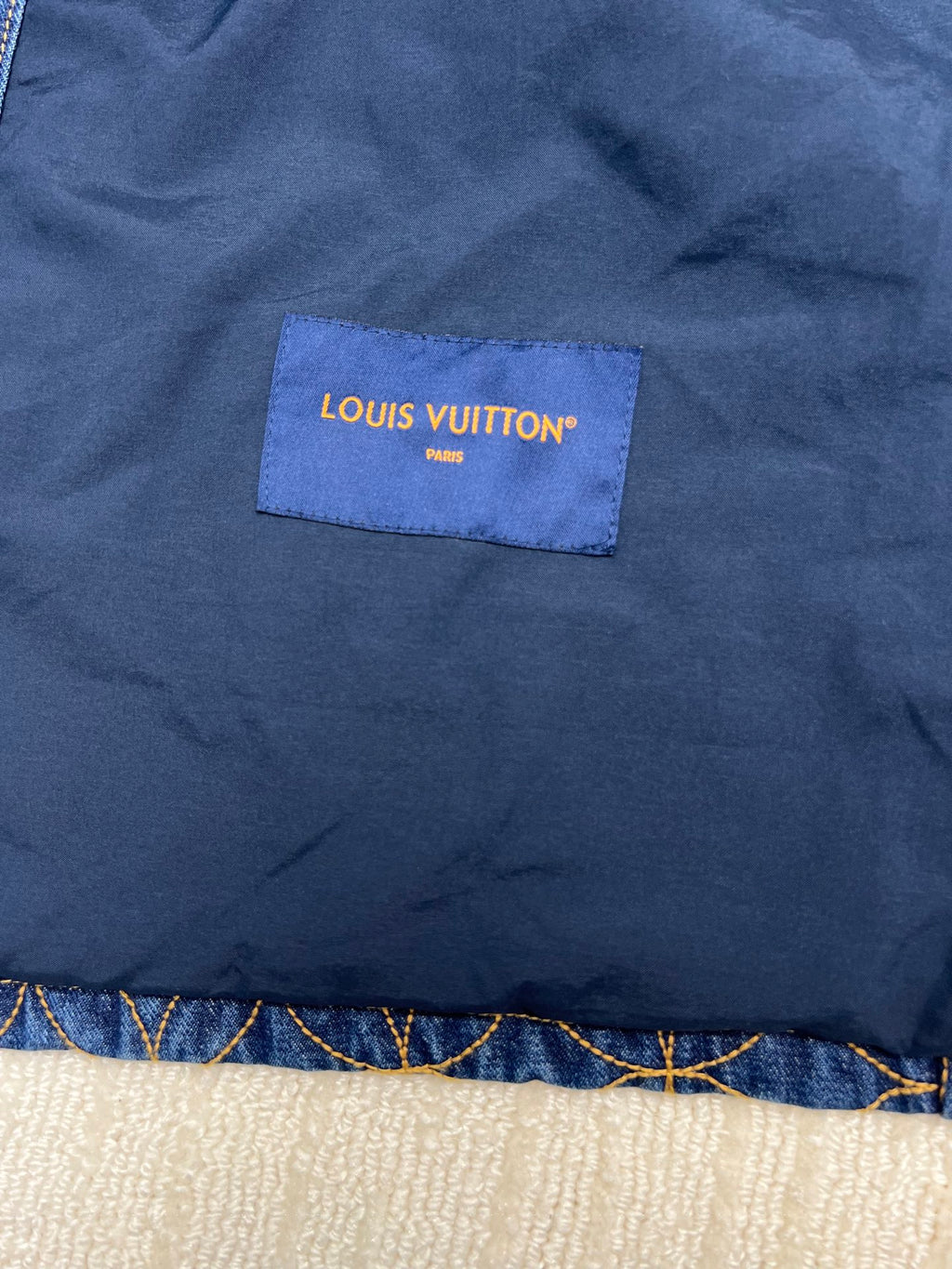 Denim jacket fabric patch label reading LOUIS VUITTON PARIS