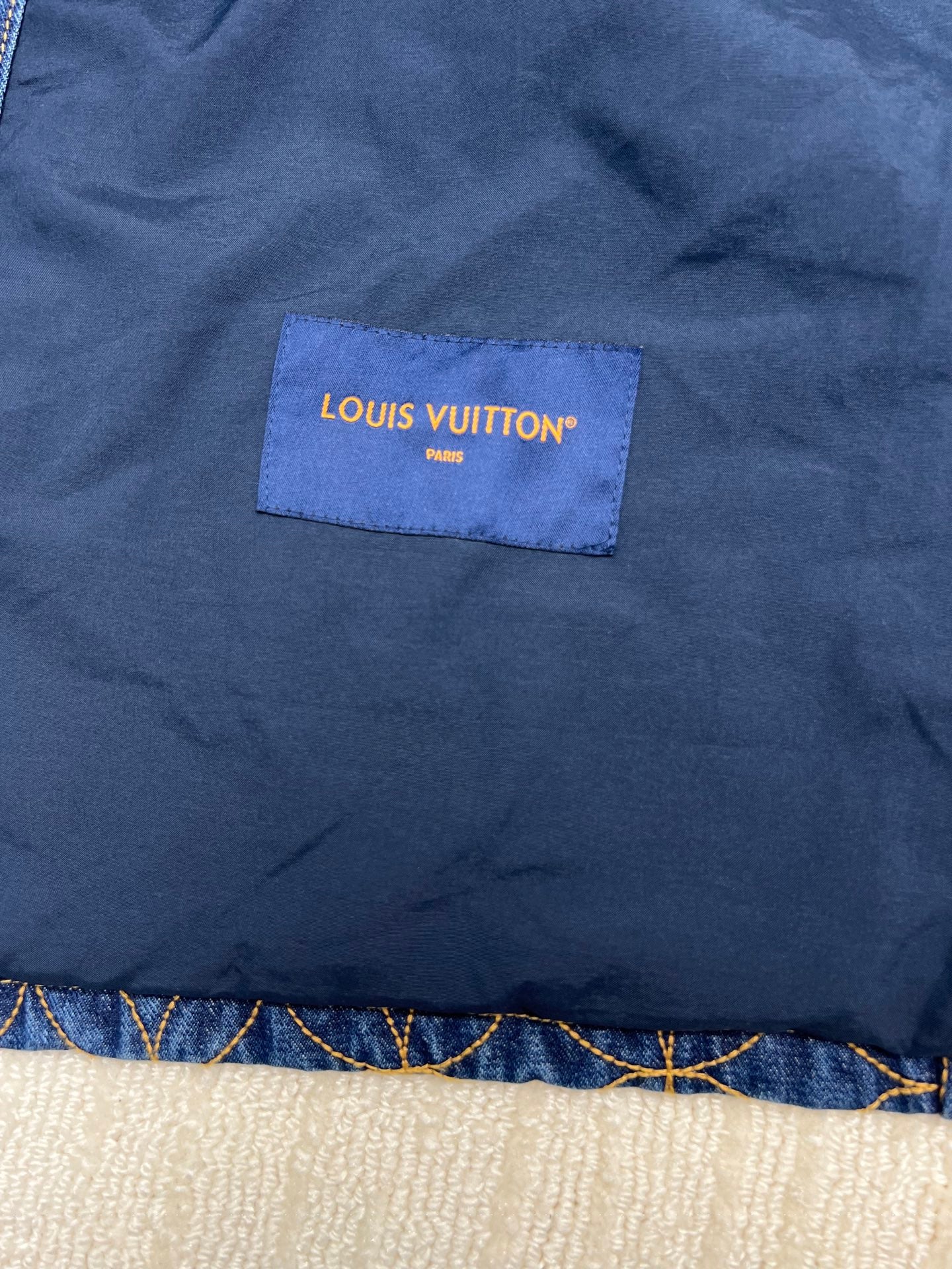 Denim jacket fabric patch label reading LOUIS VUITTON PARIS