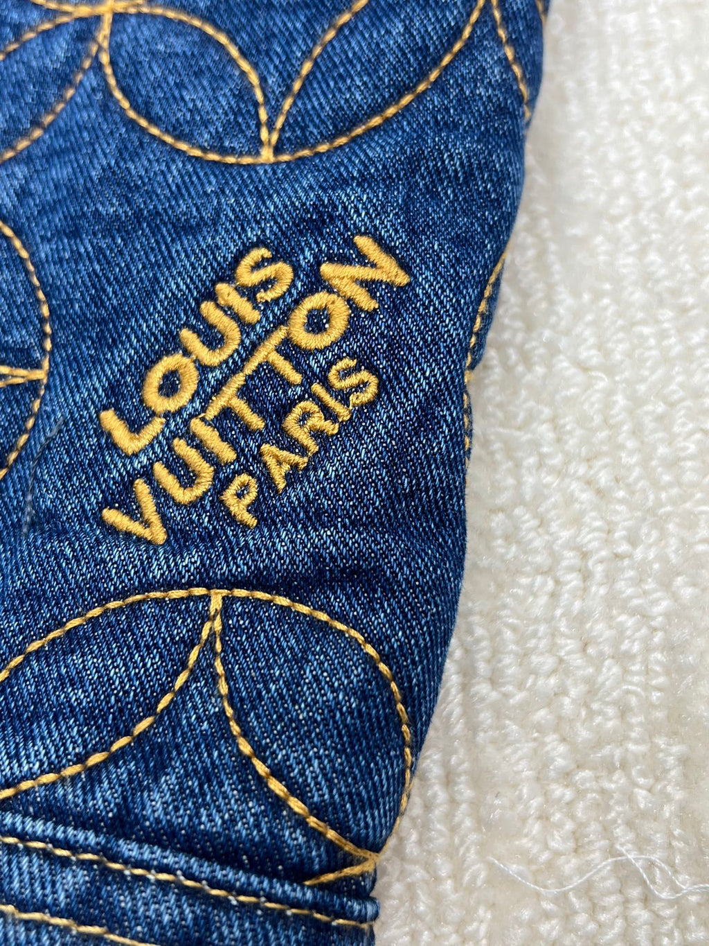 Denim jacket sleeve with embroidered Louis Vuitton Paris logo text