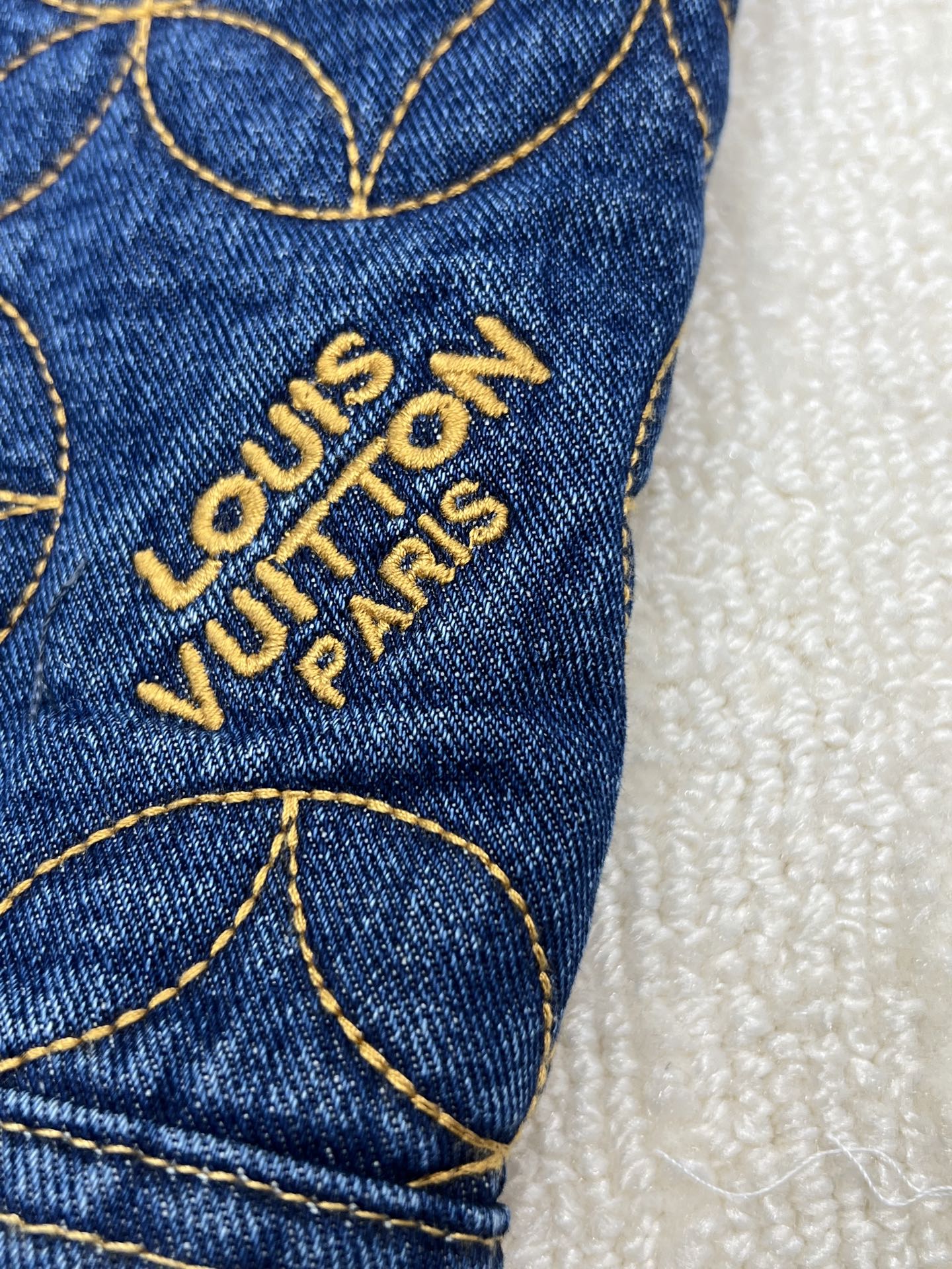Denim jacket sleeve with embroidered Louis Vuitton Paris logo text