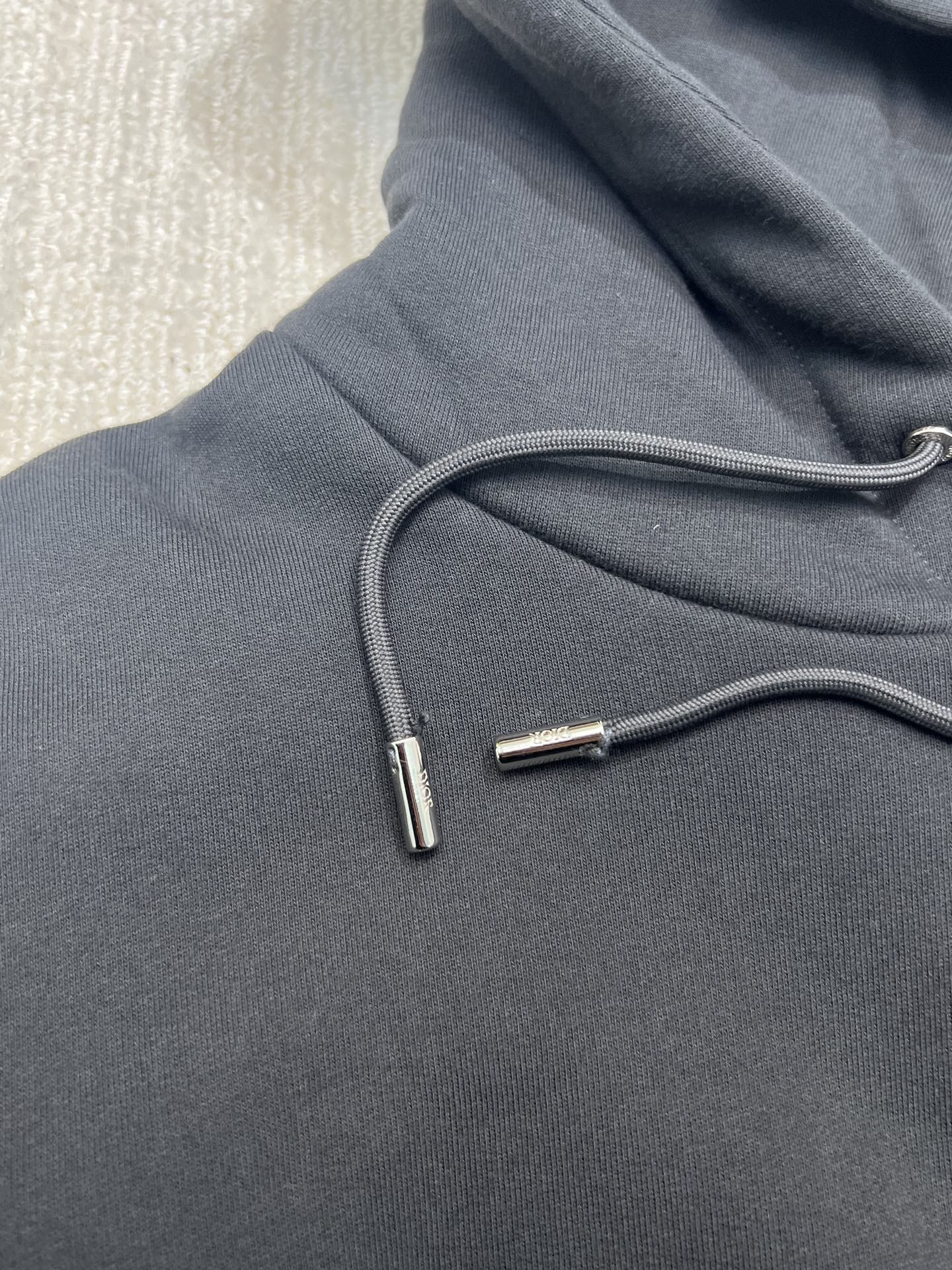 Dior hoodie drawstring and metal aglets on dark navy fabric close-up