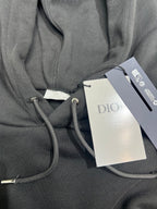 Dior hoodie detail with gray drawstring cord and interior pocket seam; attached tags