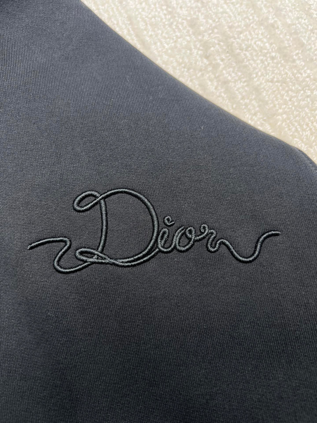 Dior hoodie embroidered logo on dark navy fabric, close-up view