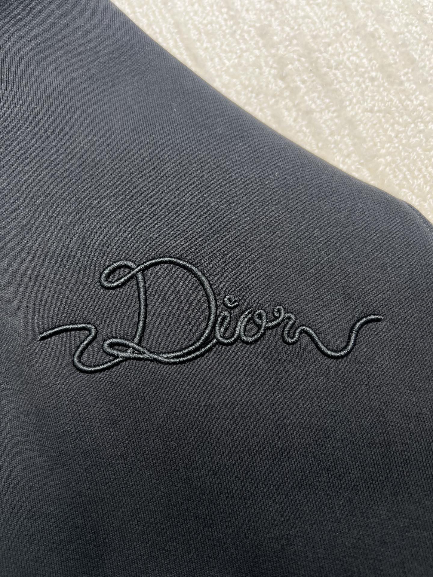 Dior hoodie embroidered logo on dark navy fabric, close-up view