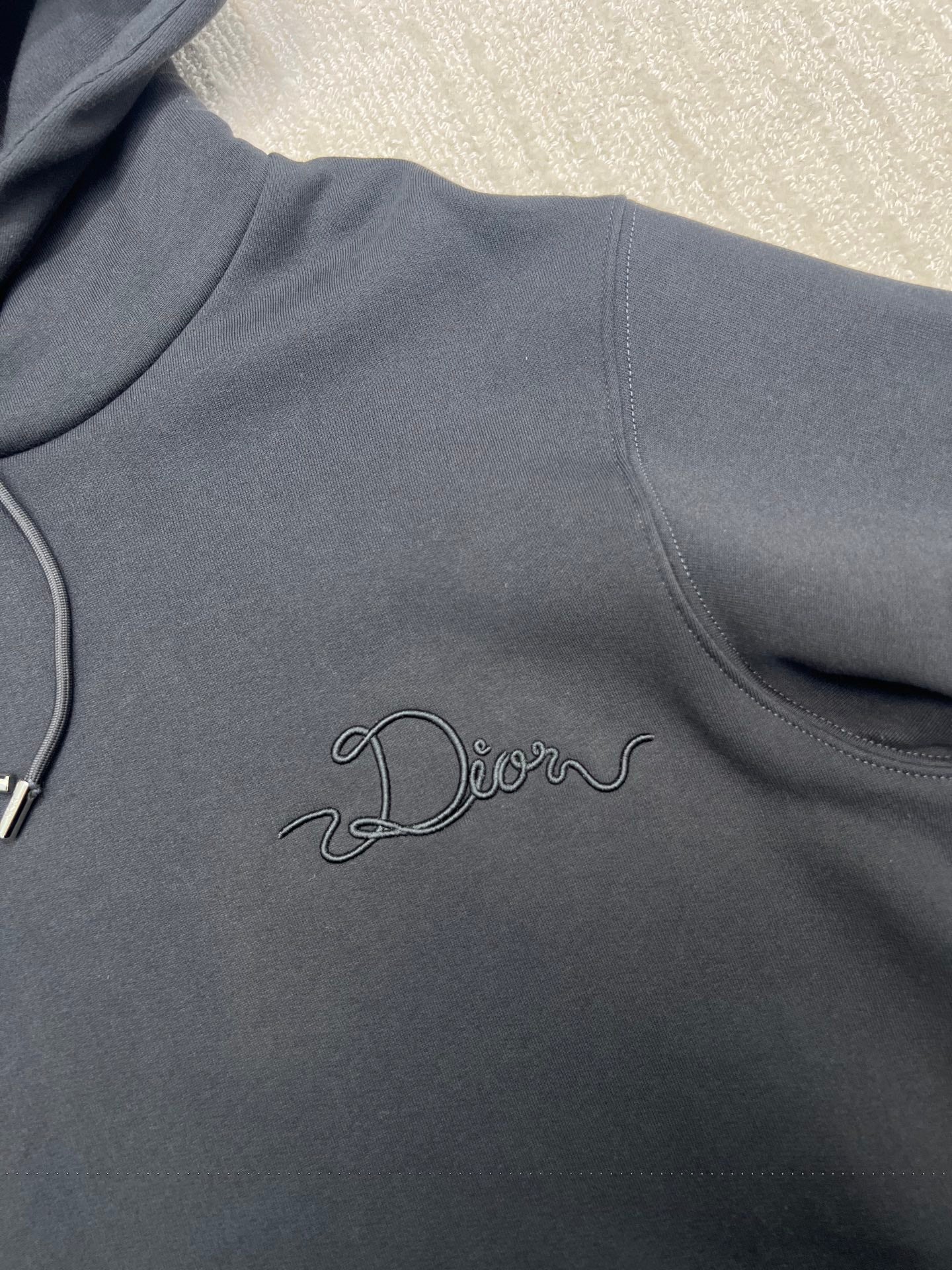 Dior hoodie front close-up with embroidered cursive logo and drawstring cord