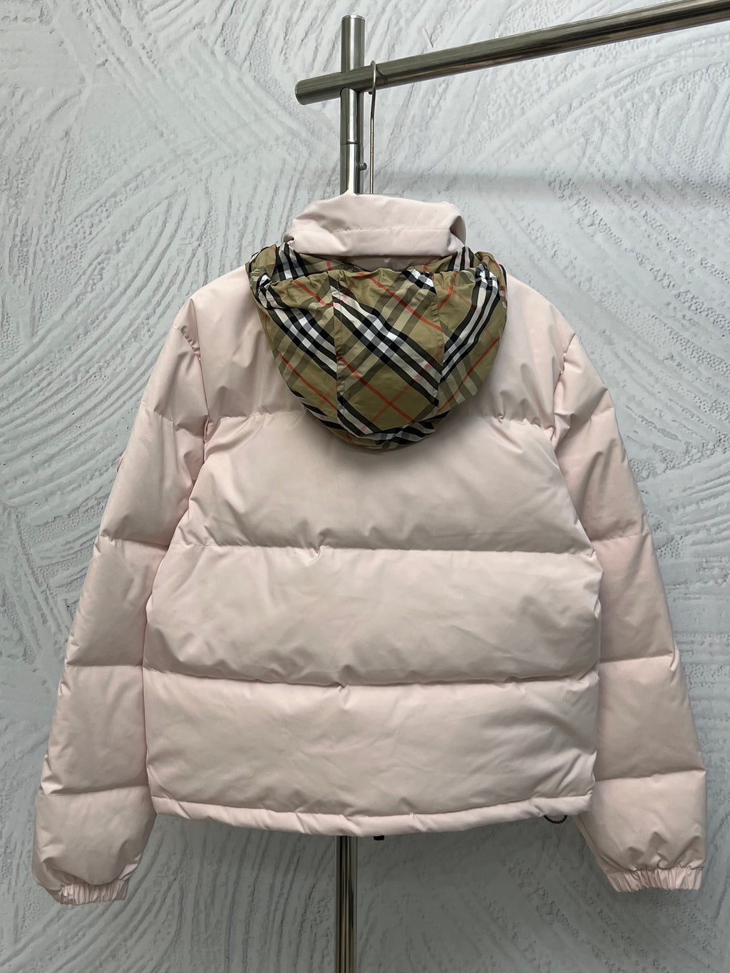 Back view long puffer jacket in light pink with plaid-lined hood.
