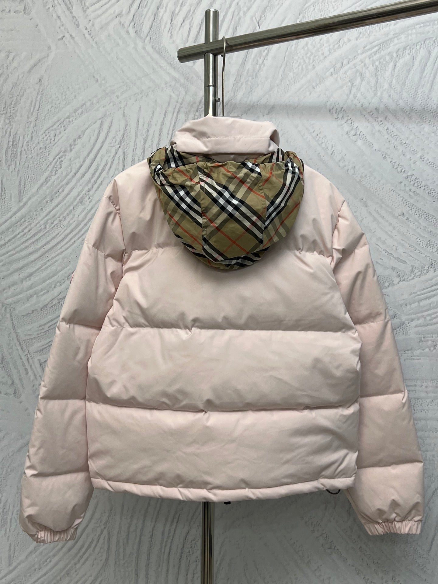 Back view long puffer jacket in light pink with plaid-lined hood.