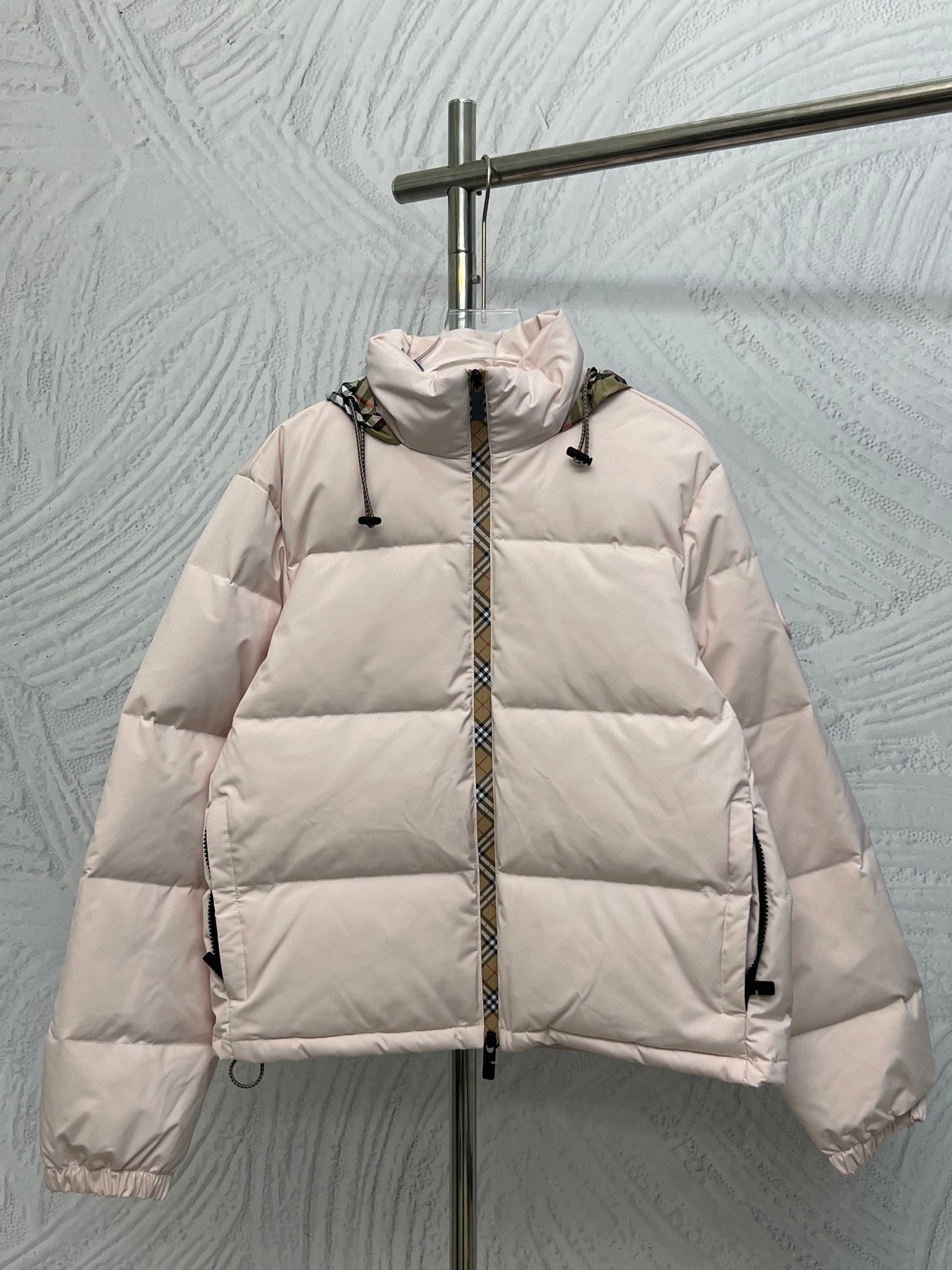 Long puffer jacket with front zip, light pink color and padded hood.