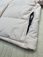 Light pink long puffer jacket with zip pull tab and stitched paneling.
