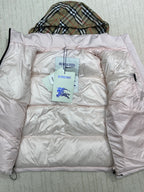 Light pink long puffer jacket laid flat, hood folded, neck label visible.