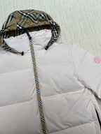 Hooded long puffer jacket detail: plaid hood lining on light pink body.