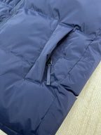 Blue puffer jacket hooded sleeve close-up with zipper pull and stitched seams