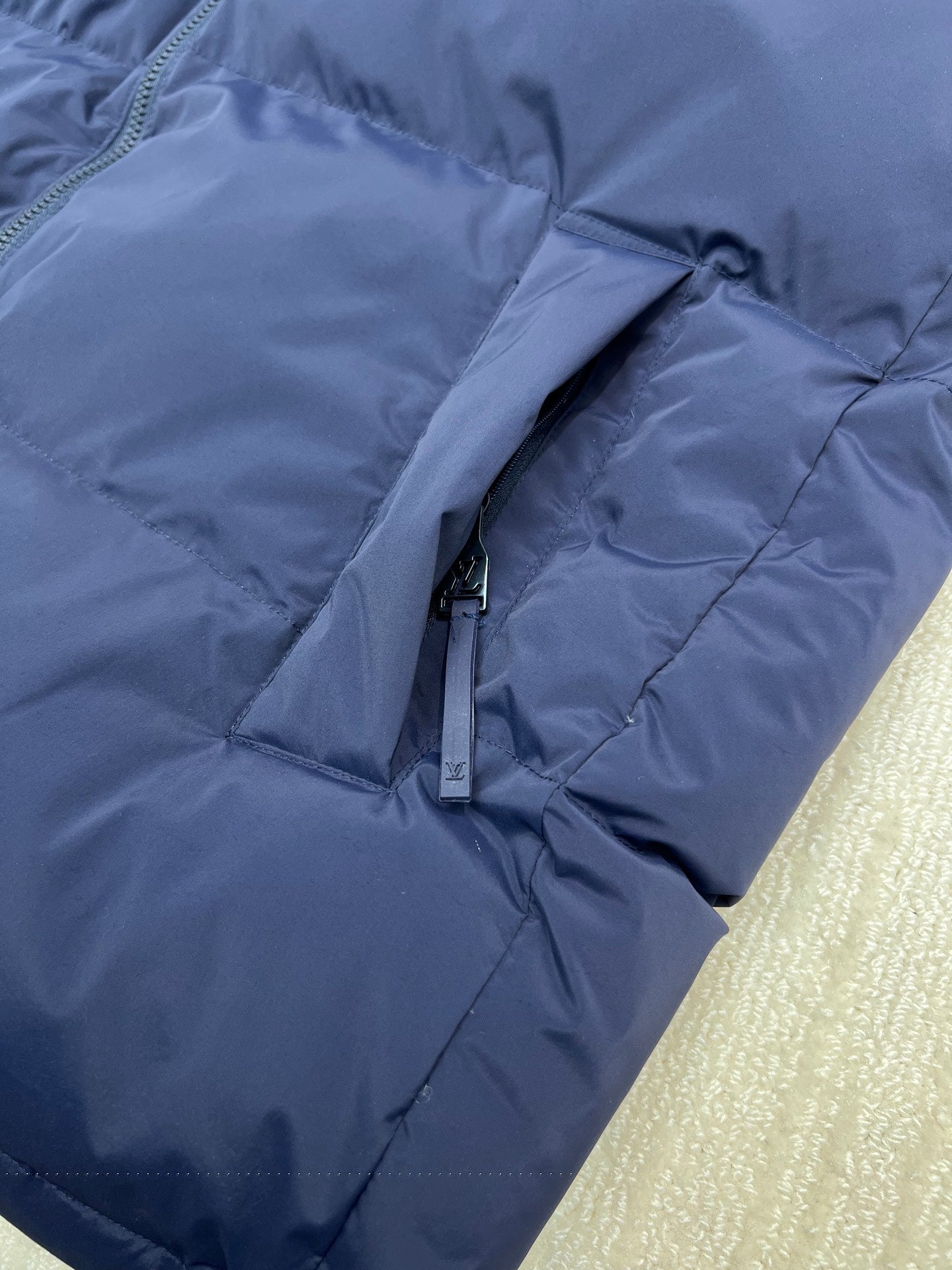 Blue puffer jacket hooded sleeve close-up with zipper pull and stitched seams