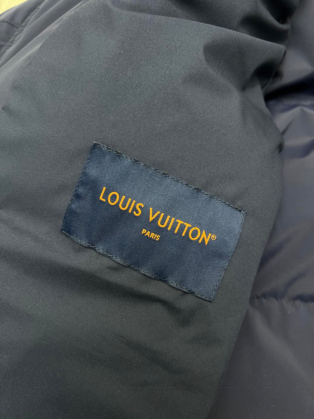 Dark fabric Louis Vuitton label patch on jacket lining, close-up