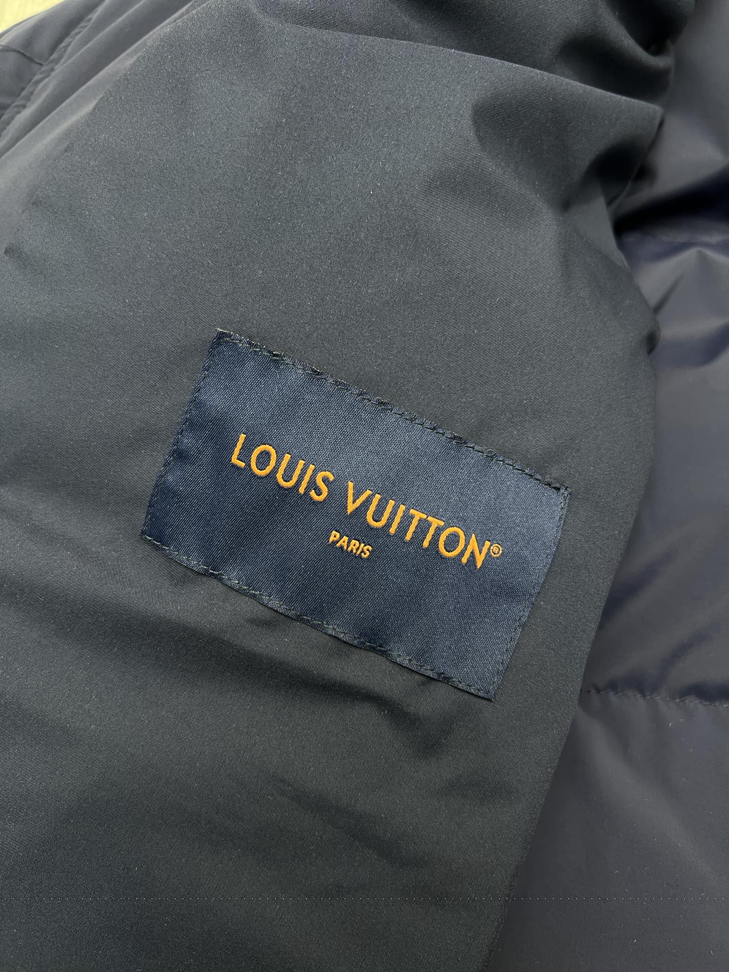 Dark fabric Louis Vuitton label patch on jacket lining, close-up