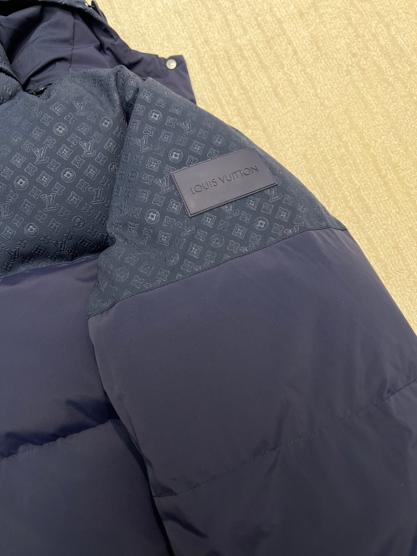 Louis Vuitton logo patch on blue hooded puffer jacket, side view of quilted fabric