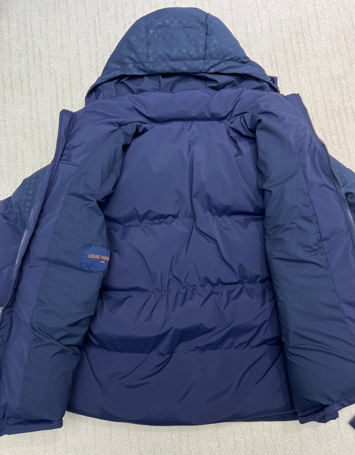 Blue hooded puffer jacket back view with central panel quilting and hood