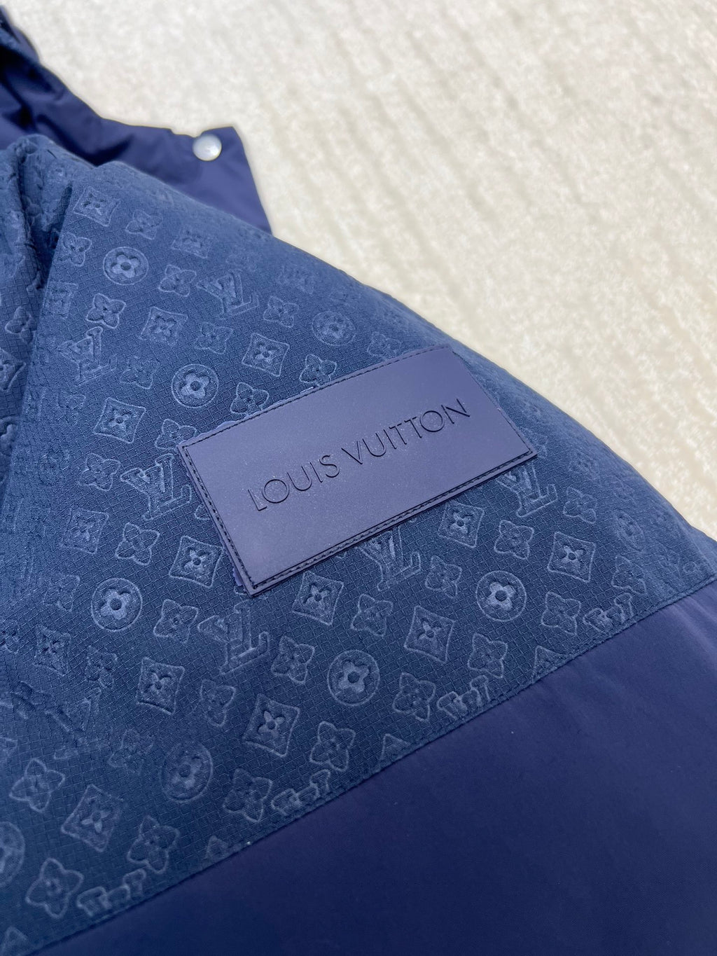 Louis Vuitton logo patch on blue hooded puffer jacket with repeating monogram pattern