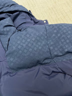 Blue hooded puffer jacket sleeve and buttoned hood trim, textured outer fabric