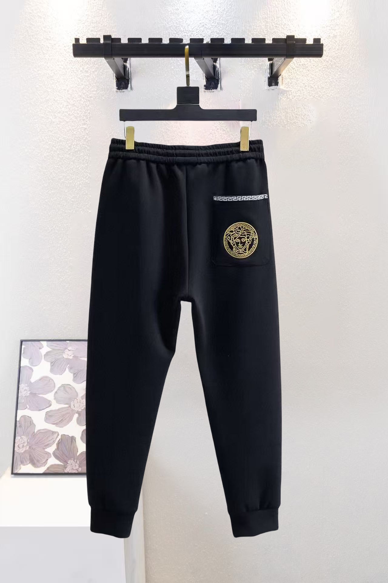 Versace black jogger pants with drawstring, elastic waist, gold pocket emblem and logo.