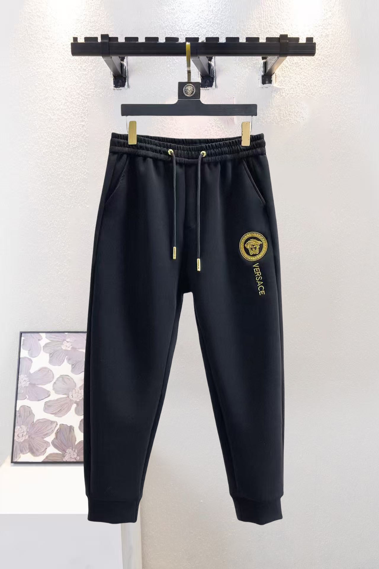 Black Versace sweatpants with elastic waistband, gold drawstrings and logo patch