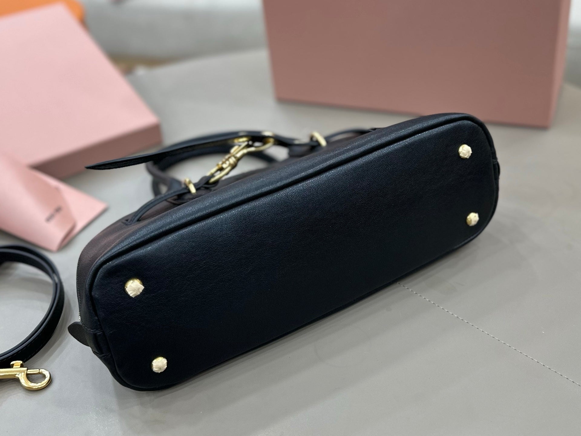 MiuMiu dark navy leather handbag bottom view with small round feet and gold-tone accents