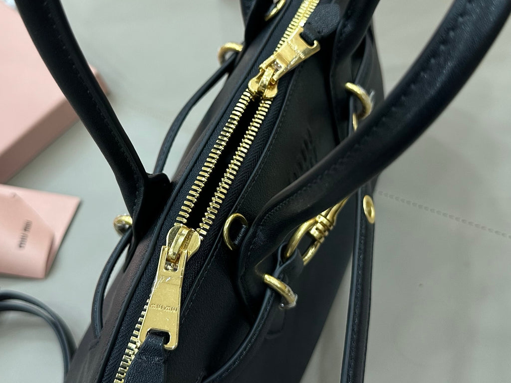 MiuMiu dark navy leather bag with visible gold-tone zipper and hardware at the side