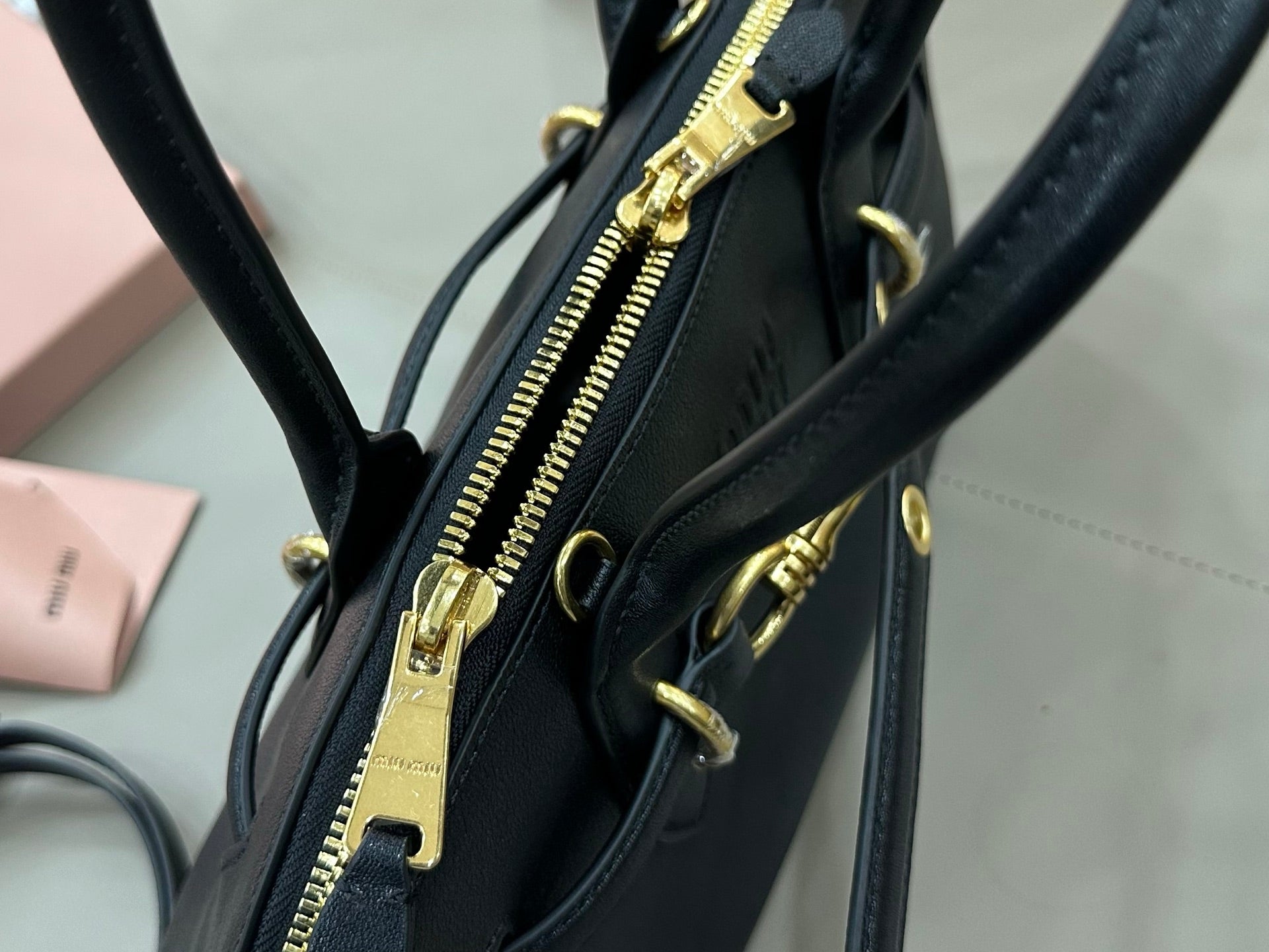 MiuMiu dark navy leather bag with visible gold-tone zipper and hardware at the side