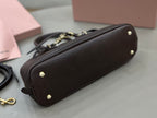 Dark leather top-handle bag side view with gold studs and zipper trim