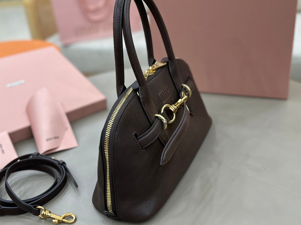 Dark leather satchel with zip top, side pocket, and gold-tone hardware