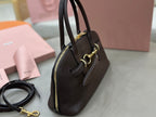 Dark leather satchel with zip top, side pocket, and gold-tone hardware