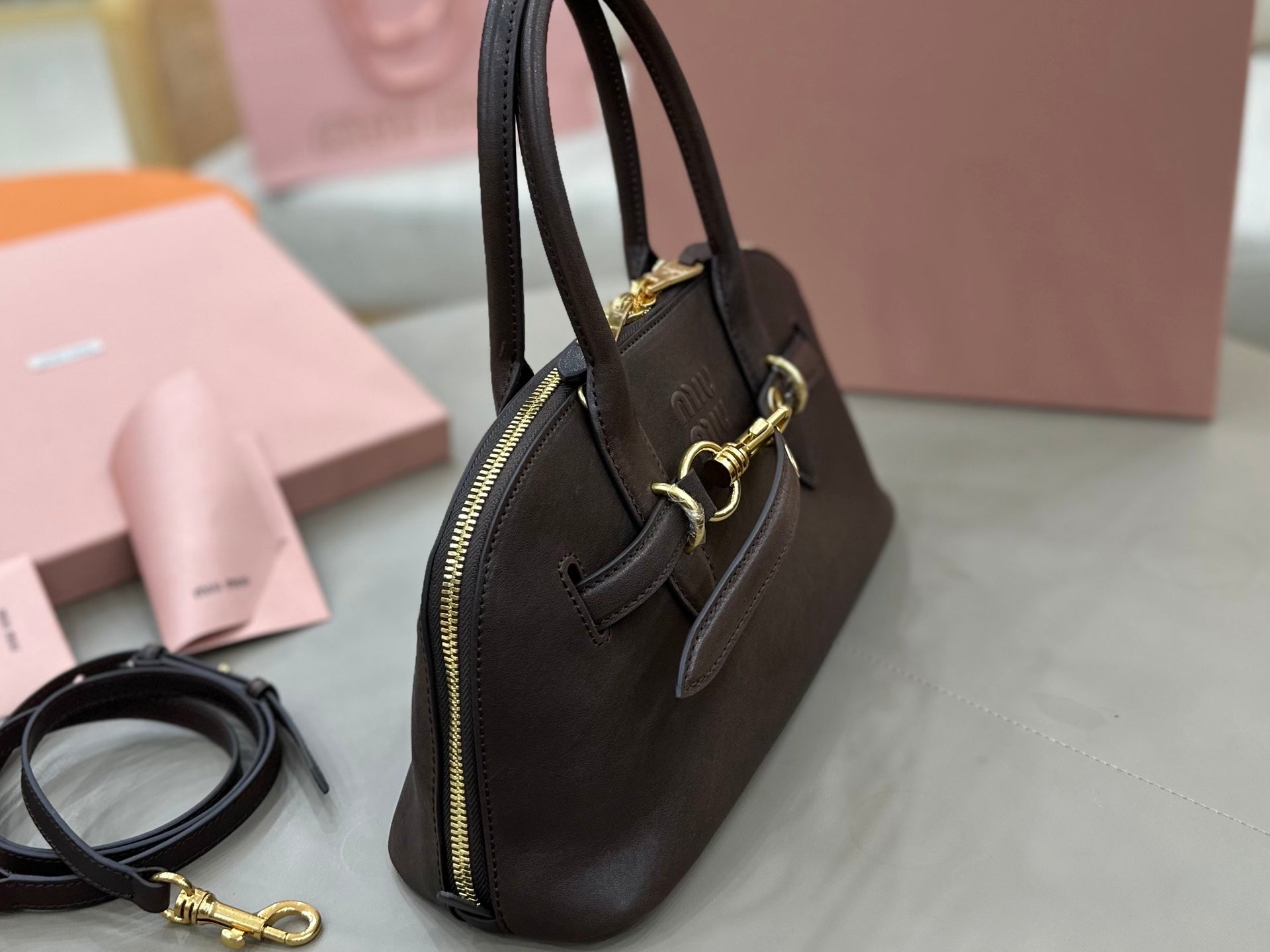 Dark leather satchel with zip top, side pocket, and gold-tone hardware