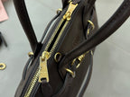 Dark leather bag close-up of gold zipper pull and side hardware