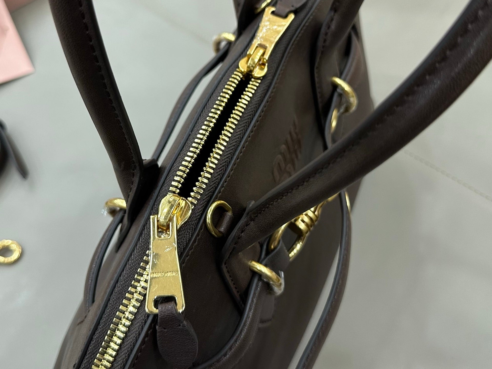 Dark leather bag close-up of gold zipper pull and side hardware