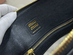 MiuMiu logo patch on black leather mini bag edge with gold zipper trim