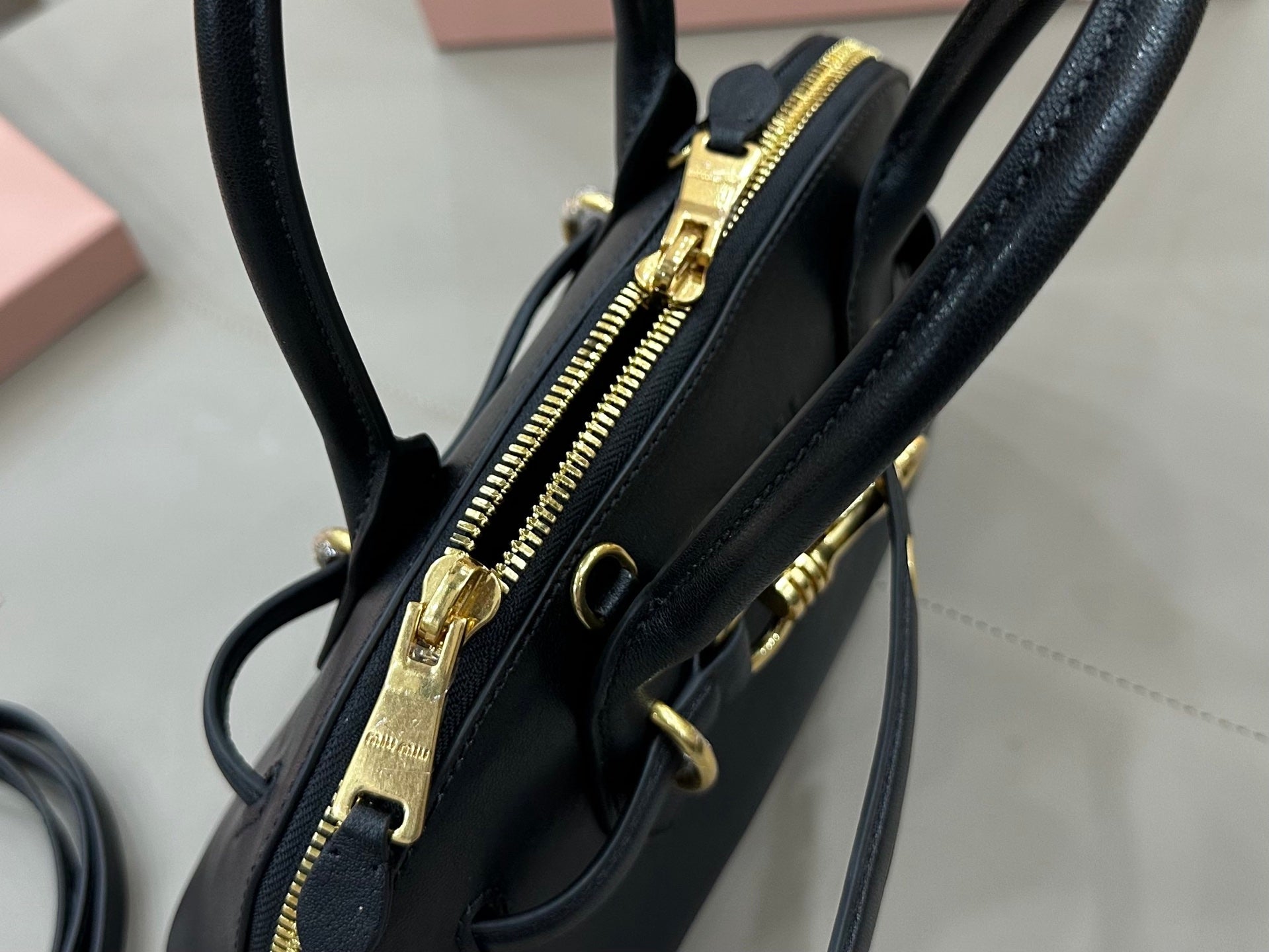 MiuMiu mini bag interior view, black with zipper pocket and gold-tone zipper