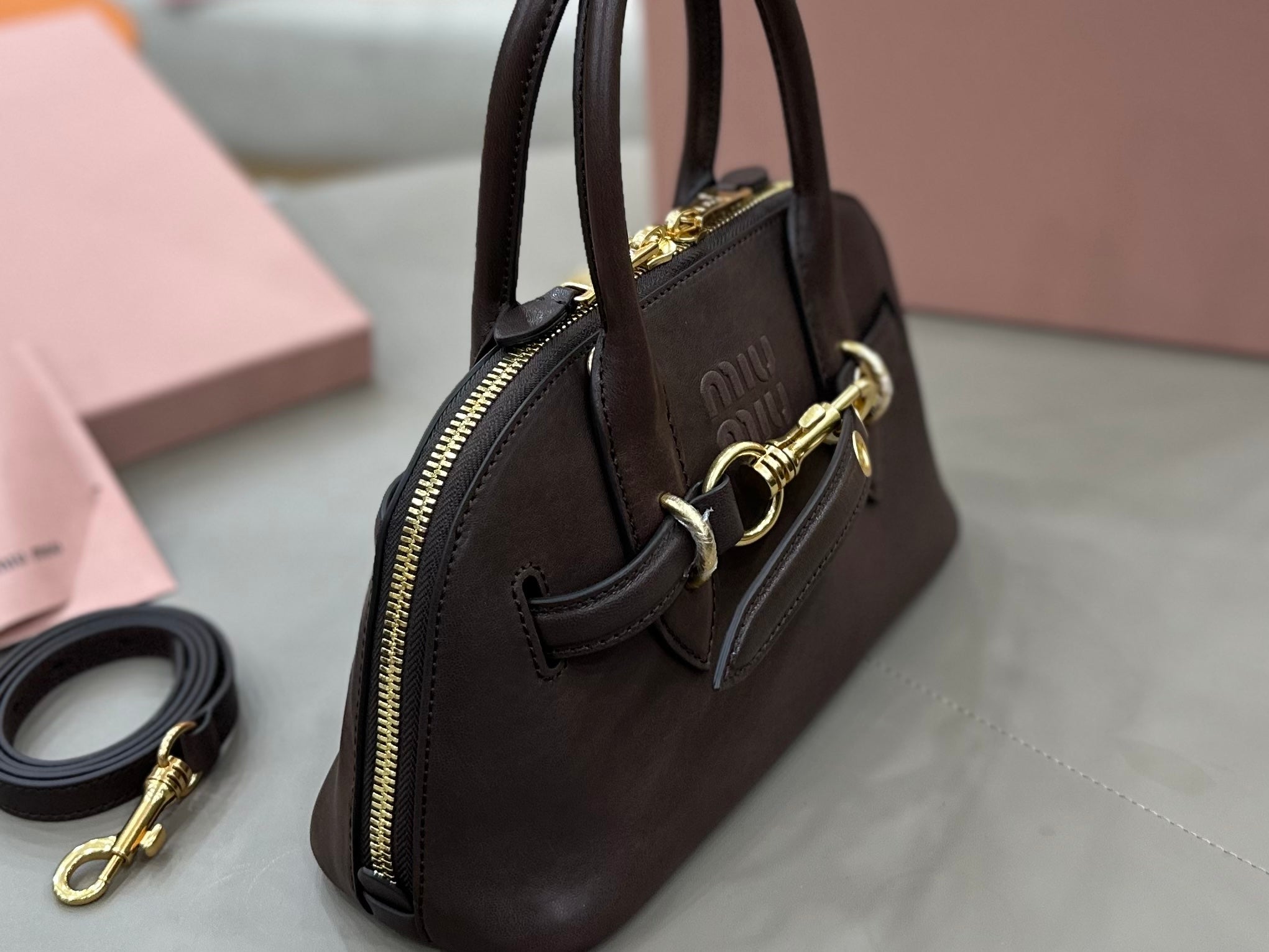 MiuMiu handbag side view with zip pocket and gold-tone hardware, dark brown