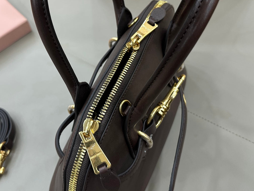 MiuMiu handbag close-up with zipper pull and gold-tone hardware, dark brown